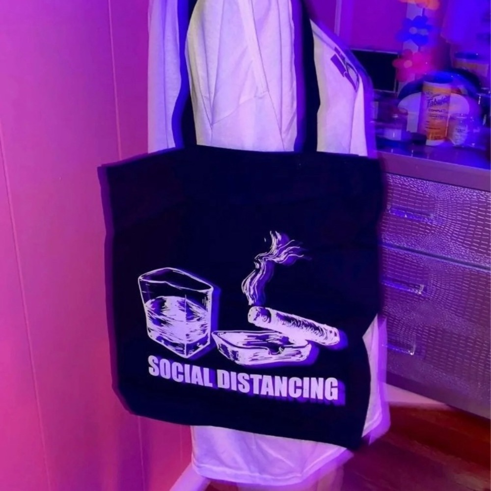 A black tote bag. The font says“Social Distancing”